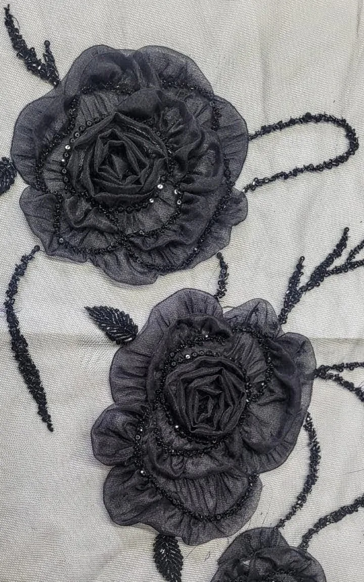Raised dark roses with curling stems and small leaves on pale transparent fabric.