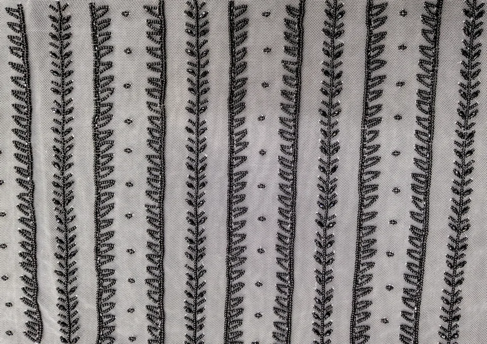Regular vertical rows of dark leafy stems and small dots on a pale net ground.