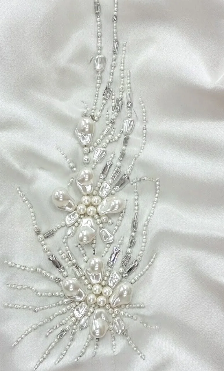 Two pale flower motifs with long fine radiating lines and rounded reflective centres.