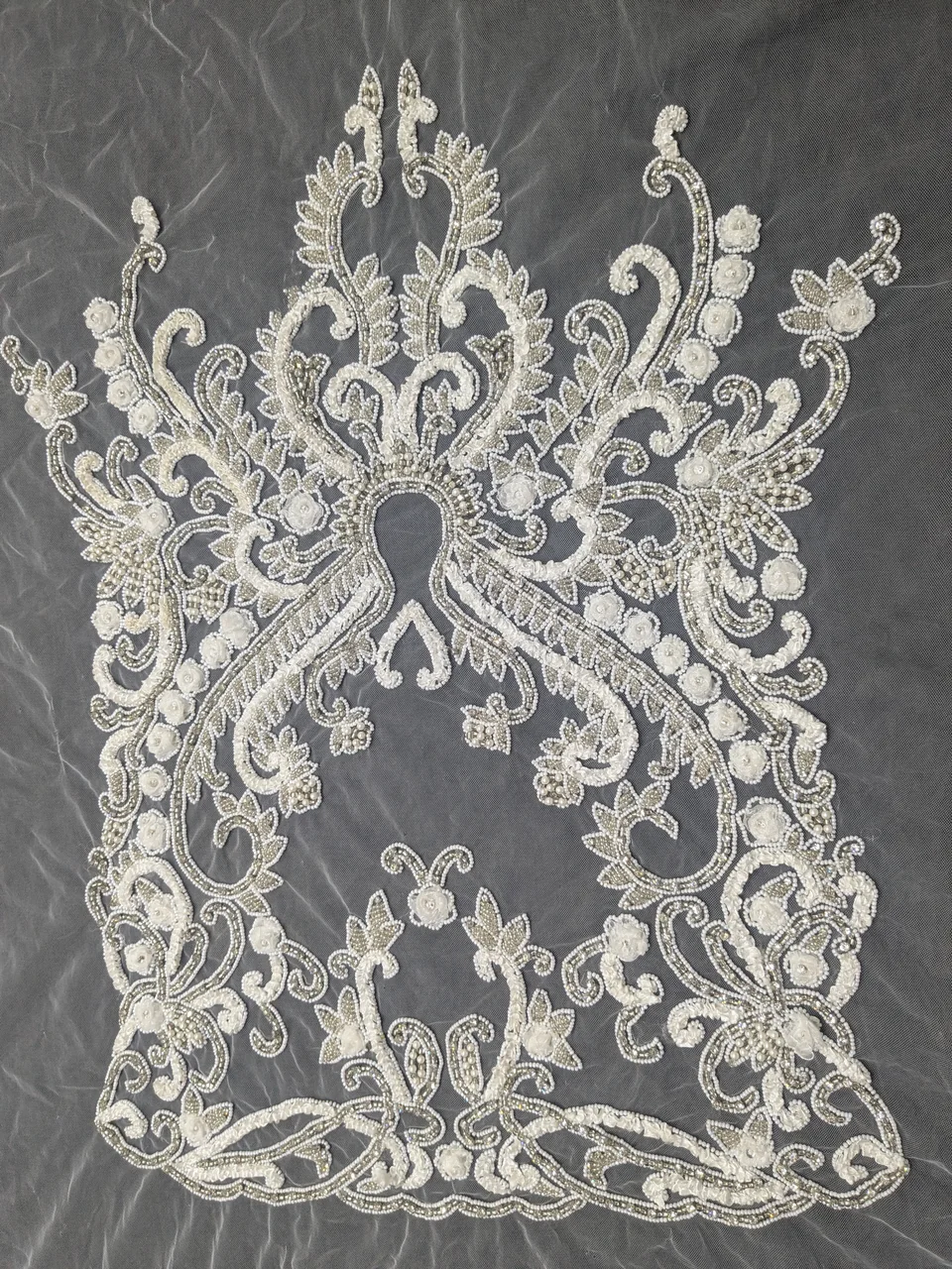 Complete pale ornamental panel with symmetrical curling stems, flowers and open spaces.