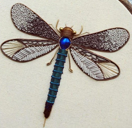 Embroidered dragonfly with metallic wing outlines, silver-toned beads and a blue body on cream fabric.